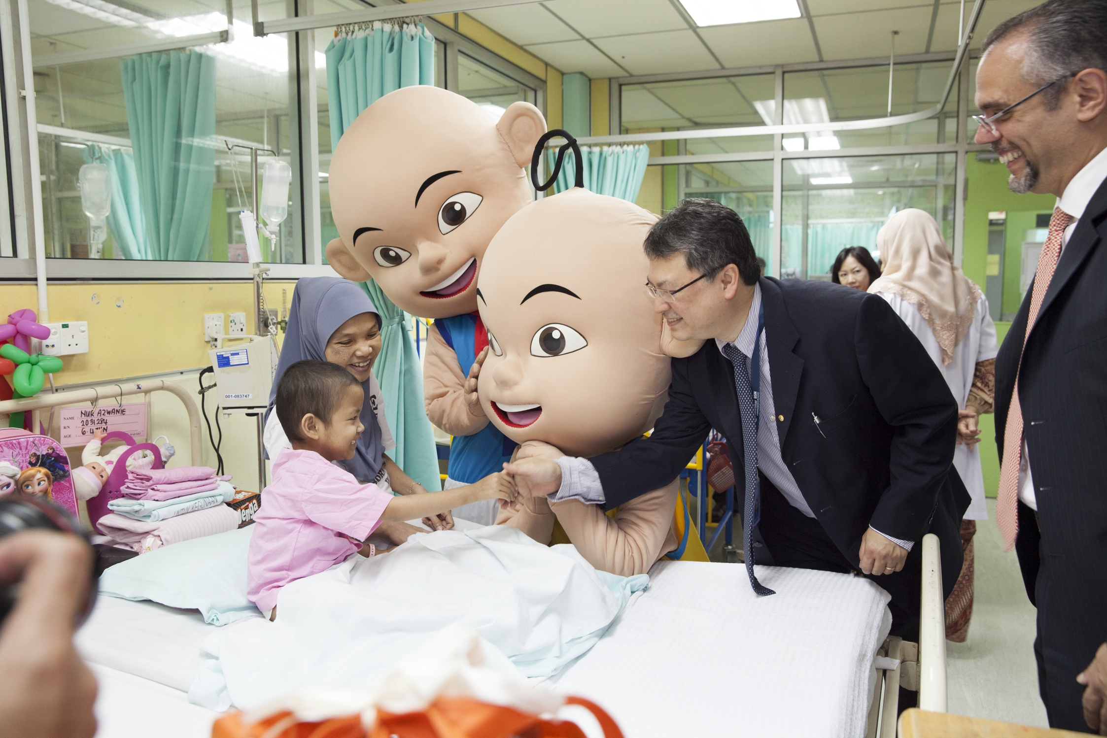 A child is enjoying the company of Upin & Ipin, LIAM President, Mr Vincent Kwo and Ramzi Toubassy, CEO of AmMetLife Insurance Berhad (far right)