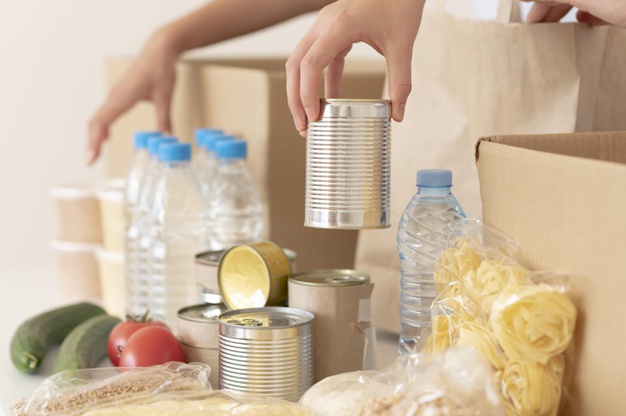 volunteers-putting-canned-food-donation-box_23-2148733772